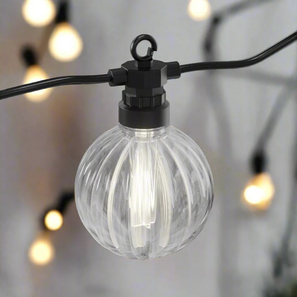 Tændt stribet LED-kugle på sort kabel med slørede lyskugler i baggrunden